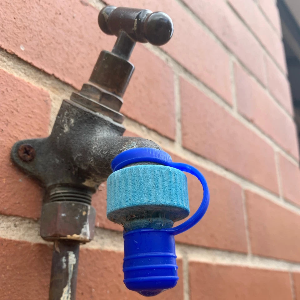 Outdoor faucet with a blue cap attached to a brick wall
